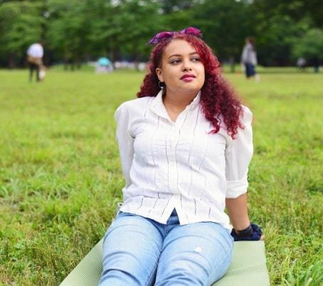 Red-haired-individual-sitting-on-a-mat-on-grass