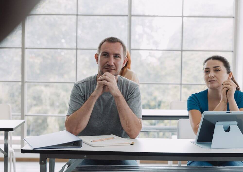 two-people-with-gadget-and-a-notebook-at-a-table