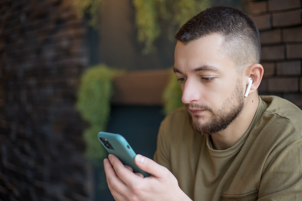 person-using-smartphone-and-earbuds