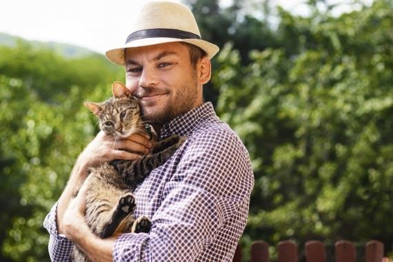 person-wearing-straw-hat-holding-a-tabby-cat