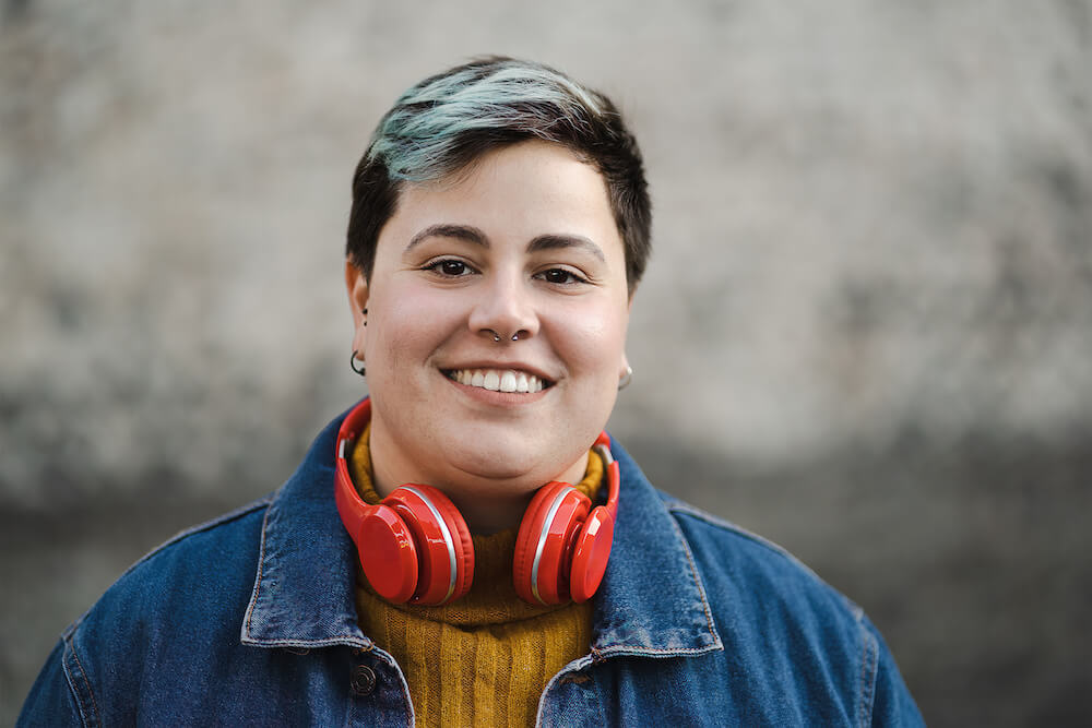 person-with-short-dyed-blue-hair-and-headphones-around-their-neck