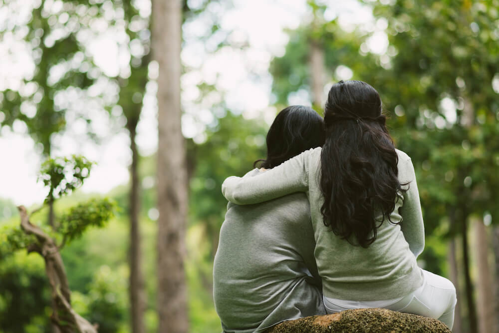 two-people-sitting-on-a-rock-one-arm-around-the-other